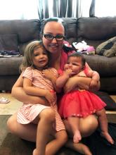 Mackenzie and her sister sitting in their mother's lap posing for a photo