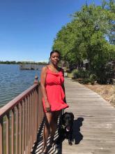 Sophia and her guide dog standing on a walkway next to a lake