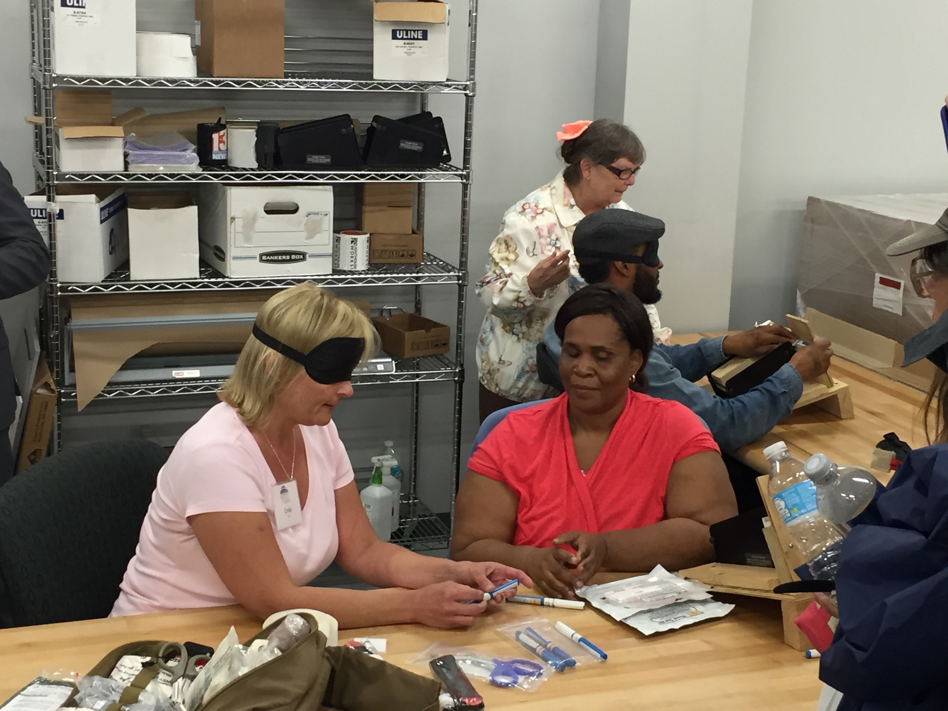 A group of attendees sitting at a table wearing blindfolds attempting various tasks